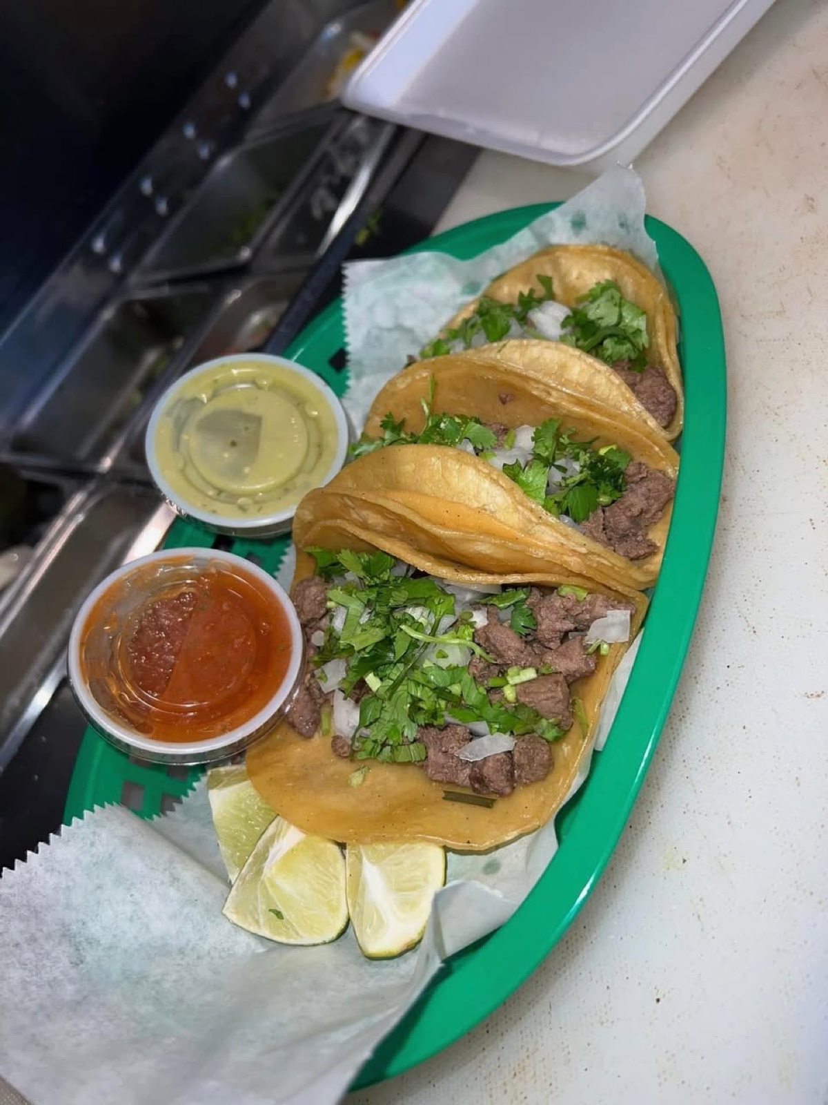 Three street tacos with cilantro and onion