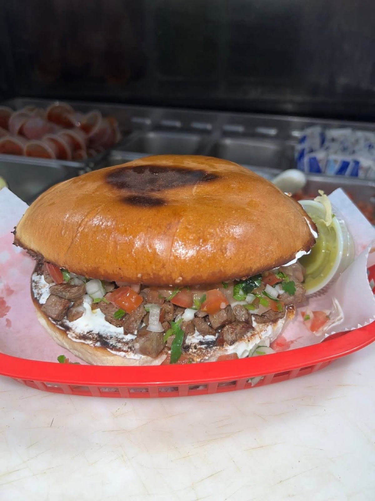 A toasted torta stacked with carne asada, crema, pico de gallo and avocado